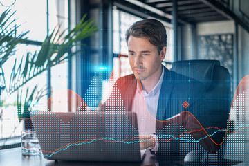 Handsome businessman in suit at workplace working with laptop to optimize trading strategy at...