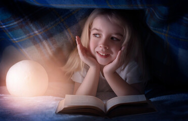 Child reading a book under the covers. Immersion into the magical world