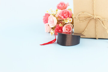 Graduation hat , brown paper gift box and flower against blue  background, Congratulation graduated concept with copy space.