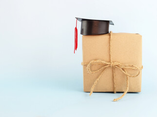 Graduation hat on brown paper gift box against blue  background, Congratulation graduated concept with copy space.