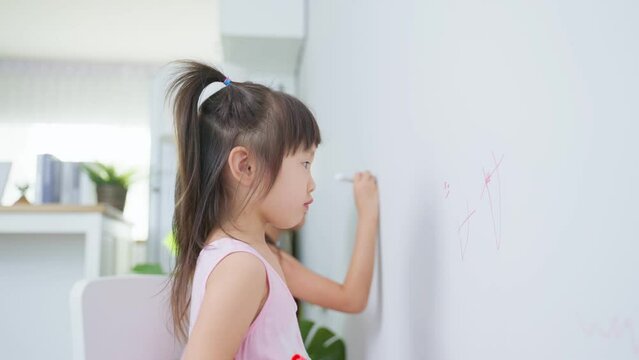 Asian young sibling kid girl enjoy paint on white wall in living room. 