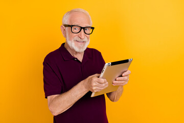 Photo of mature cheerful man chat type social media tablet app download isolated over yellow color...