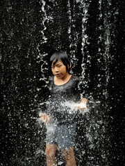 Fototapeta premium Young asian boy have fun with small waterfall