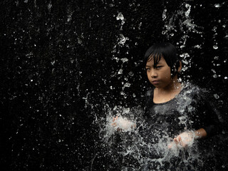 Fototapeta premium Young asian boy have fun with small waterfall