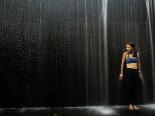 Fototapeta na wymiar Young asian woman have fun with small waterfall 