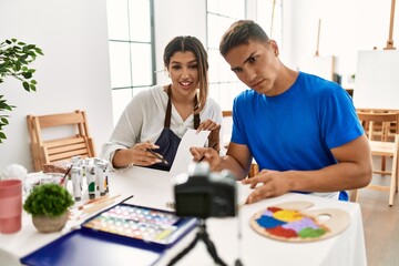 Two students smiling happy recording paint class using camera at art school.