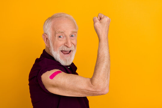 Profile side photo of senior man celebrate triumph muscles vaccinated protection isolated over yellow color background