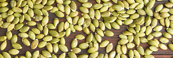 Pumpkin seeds on a wooden background banner. Healthy food. Scattered seeds of pumpkin. Flat lay
