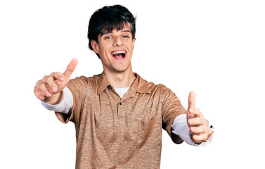 Handsome hipster young man wearing 90s retro style looking at the camera smiling with open arms for...