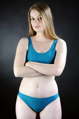 Fototapeta premium Beautiful young woman posing in blue bikini in studio 