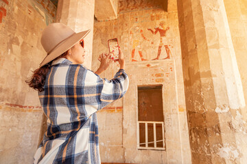 Travel blogger girl takes pictures on a smartphone at the famous Hatshepsut temple in the ancient...