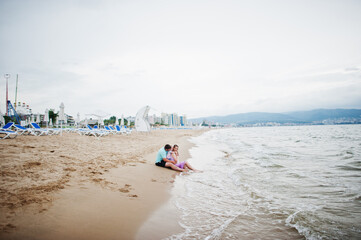 Summer vacations. Parents and people outdoor activity with children. Happy family holidays. Father, pregnant mother, baby daughter on sea sand beach.