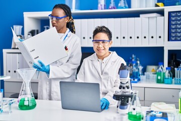 African american mother and son scientists smiling confident using laptop working laboratory