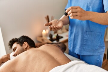 Massage therapist woman holding oil prepared to make back massage at the clinic