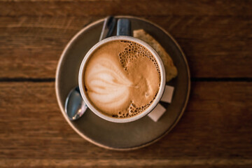 A cup of coffee on a wooden background close-up. Coffee on a platter. Coffee, biscuits, sugar and a spoon