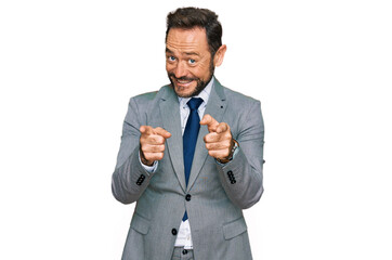 Middle age man wearing business clothes pointing fingers to camera with happy and funny face. good energy and vibes.