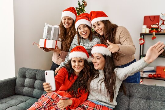 Group of young hispanic women on christmas meeting make selfie by the smartphone at home.