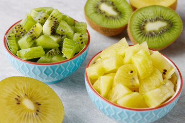 Kiwifruit of different types colors: green kiwi fruit and golden yellow kiwi. Salad cut in bowls.