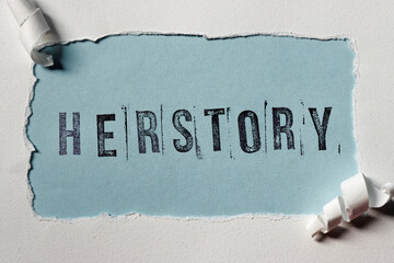 Herstory word with stamp letters on a torn paper frame. Feminism and female history concept.