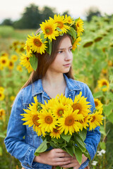 Little beautiful girl in the field
 with a wreath of sunflowers on his head with a bouquet in his hands.