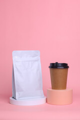 Coffee set mock up on podium isolated over pink background. White standing pouch with valve and paper cup. Realistic set mock up for branding,  template for your design, presentation, promo, ad.