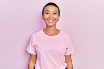 Beautiful hispanic woman with short hair wearing casual pink t shirt with a happy and cool smile on...