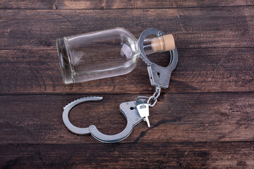 The concept of liberation from alcohol addiction, a bottle of alcohol and unfastened handcuffs