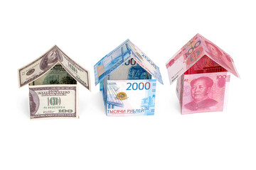 Houses made of dollars, rubles and yuan, isolated on a white background