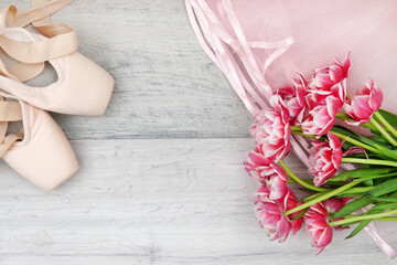 ballet, pointe shoes, tutu and bouquet of flowers on wooden background
