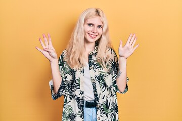 Beautiful caucasian woman with blond hair wearing tropical shirt showing and pointing up with...