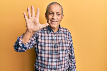 Handsome senior man with grey hair wearing casual shirt showing and pointing up with fingers number five while smiling confident and happy.