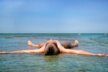 A girl sunbathes in the sea
