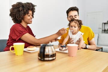 Couple and daughter having breakfast sitting on table at home