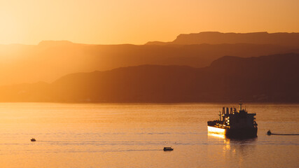 View of Aqaba Gulf at sunset with a boat, calm sea, jordan harbour for goods and sea transportation. Touristic destination on the Red Sea