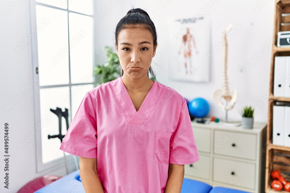 Sticker young hispanic woman working at pain recovery clinic depressed and worry for distress, crying angry 