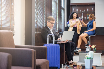 Fototapeta premium Young businessman looking at laptop screen. Handsome caucasian businessman chatting with clients online, search helpful information on internet while waiting for his flight at airport lounge.