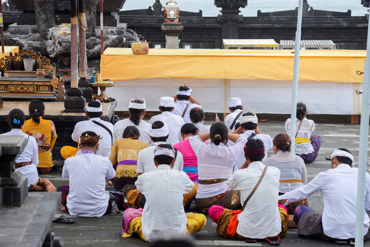 Back view of Balinese people with traditional clothes praying together 