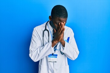 Young african american man wearing doctor uniform with sad expression covering face with hands while crying. depression concept. - Powered by Adobe