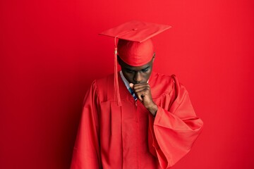 Young african american man wearing graduation cap and ceremony robe feeling unwell and coughing as...