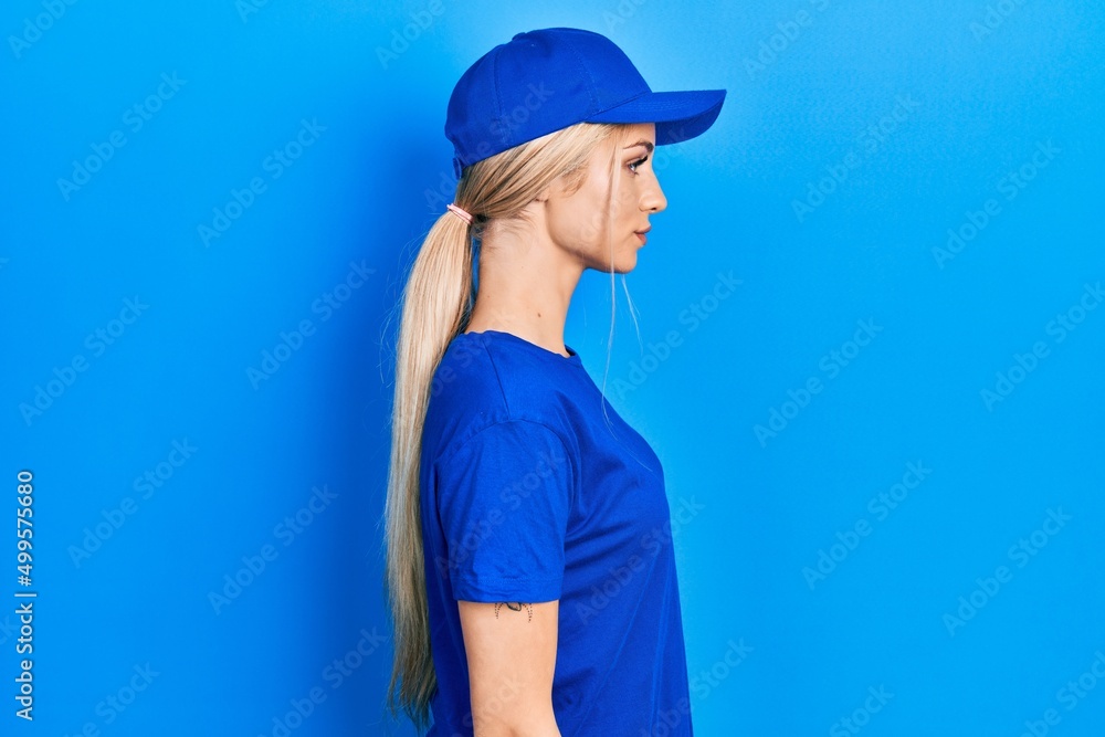 Poster young caucasian woman wearing courier uniform wearing cap looking to side, relax profile pose with n