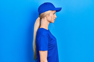 Naklejka premium Young caucasian woman wearing courier uniform wearing cap looking to side, relax profile pose with natural face with confident smile.
