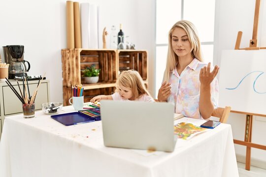Mother and daughter smiling confident having video call drawing at art studio