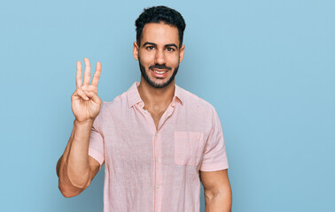 Fototapeta premium Hispanic man with beard wearing casual shirt showing and pointing up with fingers number three while smiling confident and happy.