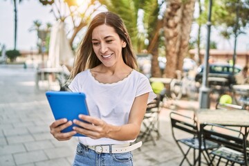 Young hispanic woman smiling confident using touchpad at street