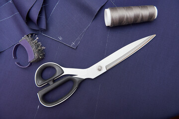 Scissors and tailor tools on blue fabric. Fabric cutting. Clothes sewing. Clothing repair. Tailoring. Close up view. Top view