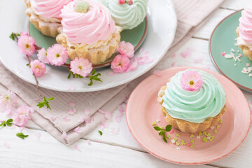 pink and green cupcakes with spring flowers on white wooden background