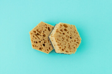 Two natural sea sponges washing dishes. Turquoise background.