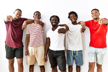 Obraz premium Young african group of friends standing together over isolated background pointing to you and the camera with fingers, smiling positive and cheerful