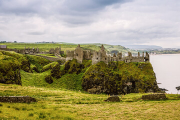 Ruins of Dunluce Castle, Antrim, Northern Ireland during sunny day with semi cloudy sky. Irish...