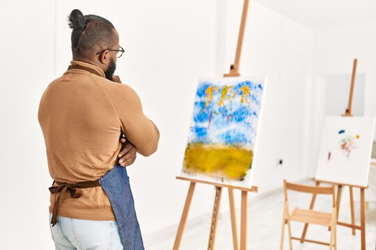 Young african american artist man on back view looking draw at art studio.